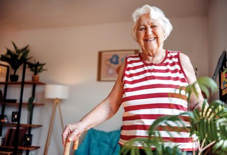 A woman smiling and holding a cane.