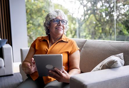 A woman on a couch using a tablet.