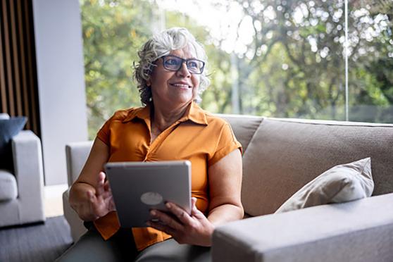 A woman on a couch using a tablet.